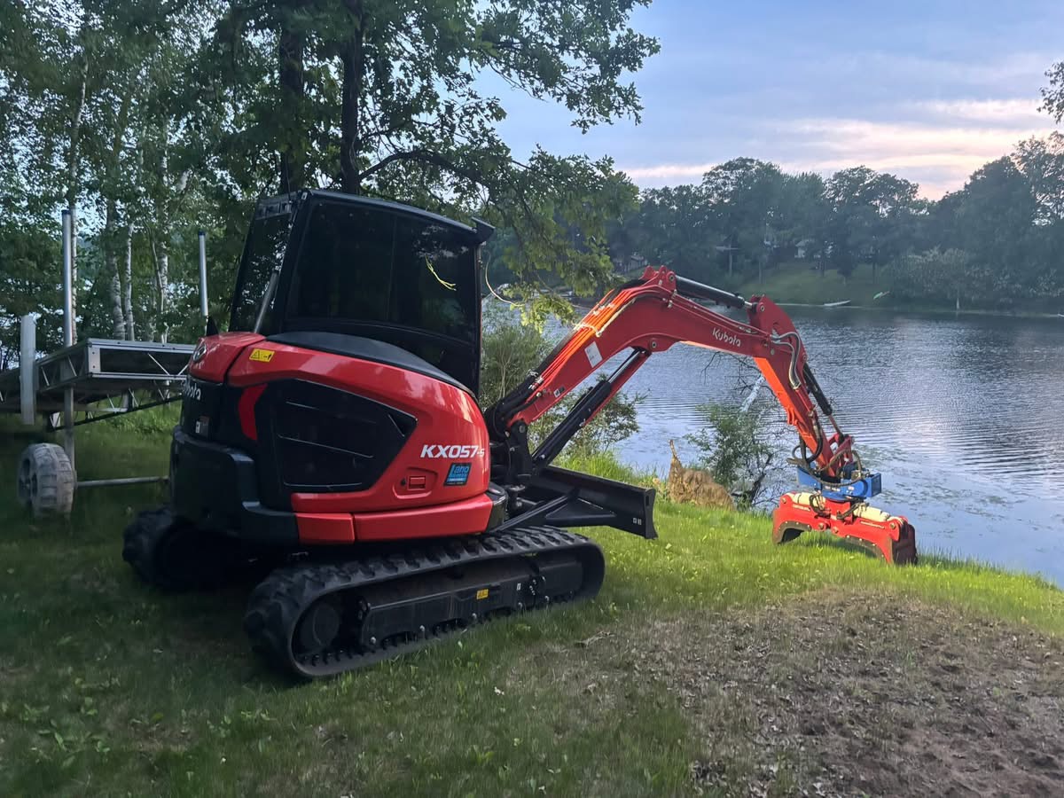 Kubota KX057 excavator on a lakeside jobsite at golden hour